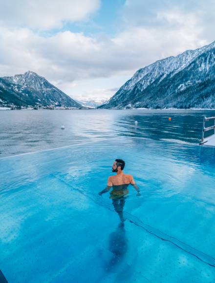 Mann im Infinity Pool des Hotel Entners am Achensee vor Bergpanorama