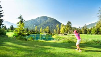 Frau beim Abschlag auf Golfplatz