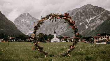 Blumenkranz vor Dorf mit Gebirgspanorama