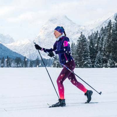 Frau beim Langlauf vor Bergkulisse